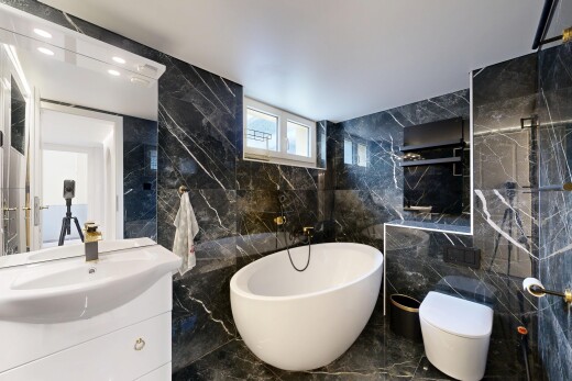bathroom featuring tile walls, vanity, a freestanding bath, marble tiled floors, and stone wall