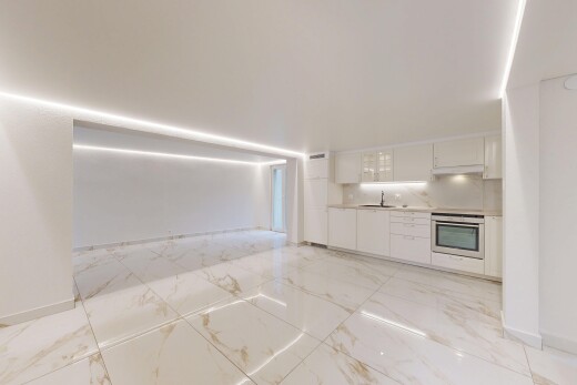 kitchen with white cabinetry, light countertops, stainless steel oven, glass insert cabinets, and light marble finish flooring