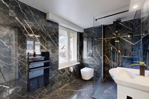 bathroom featuring vanity, marble tiled floors, stone wall, a marble finish shower, and tile walls