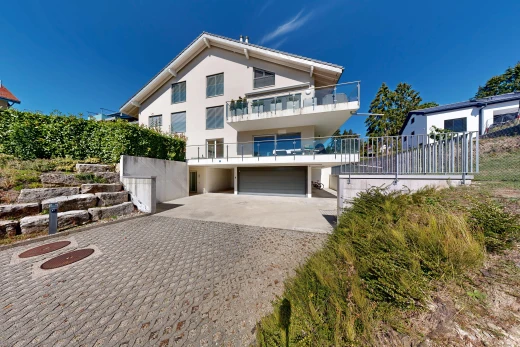 façade avec balcon, allée, garage intégré, bardage en stuc, et garage au sous-sol