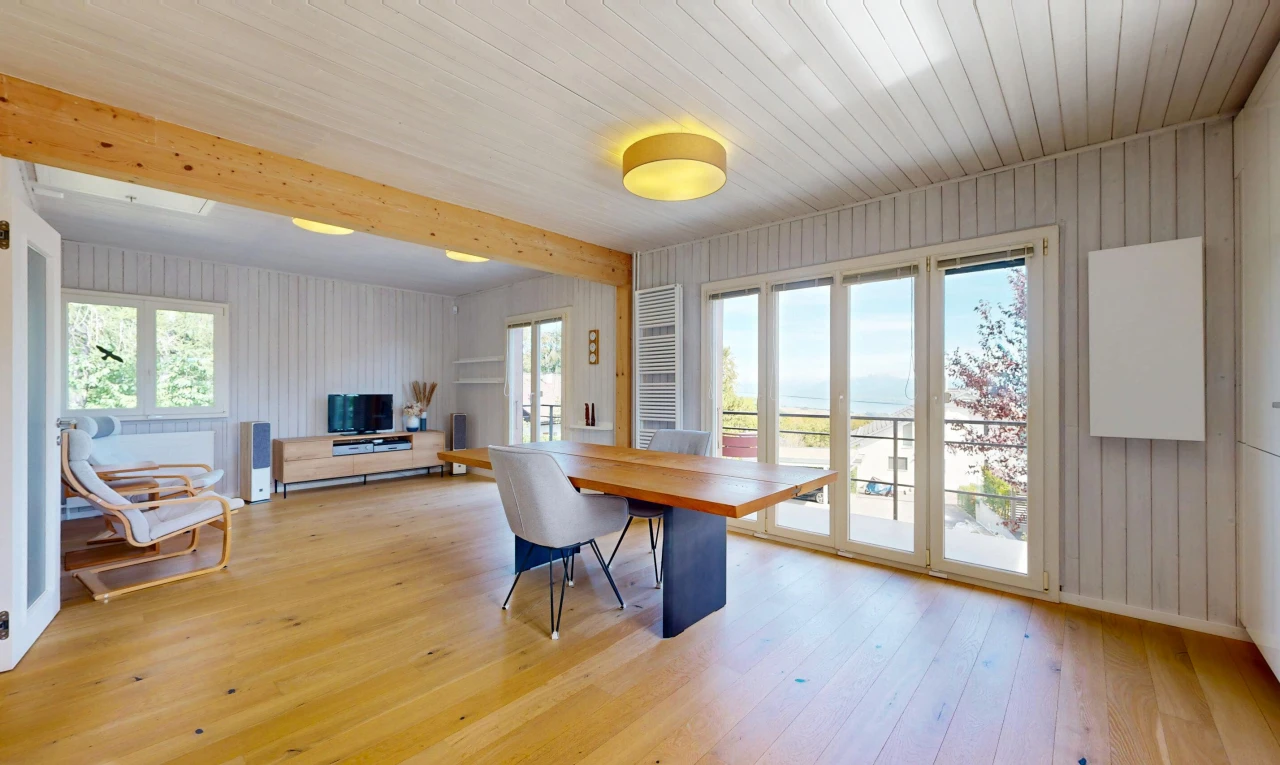 salle à manger avec high end ceiling, wood finish floor, sol en finition bois, télévision, et wood wall