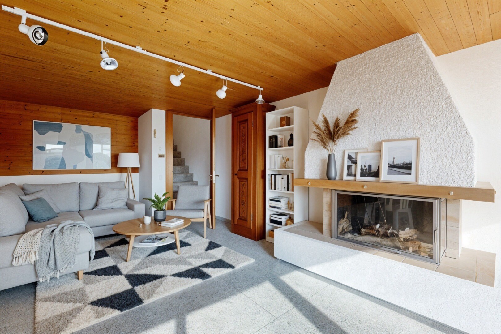 salon avec éclairage sur rail, track lighting, cheminée, plafond en bois, et wood ceiling
