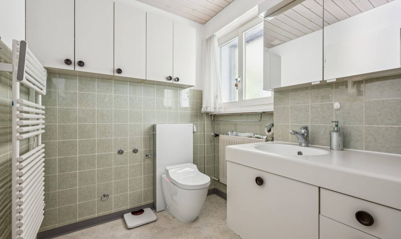salle de bains avec chauffe-serviettes, miroir, lavabo (ou coiffeuse selon le contexte), radiateur, et toilette