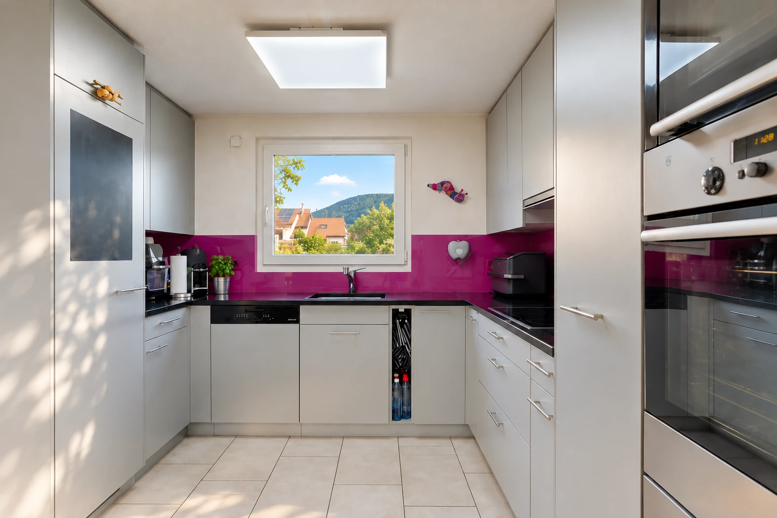 cuisine avec four, plans de travail, dark countertops, light floor, et lumière naturelle