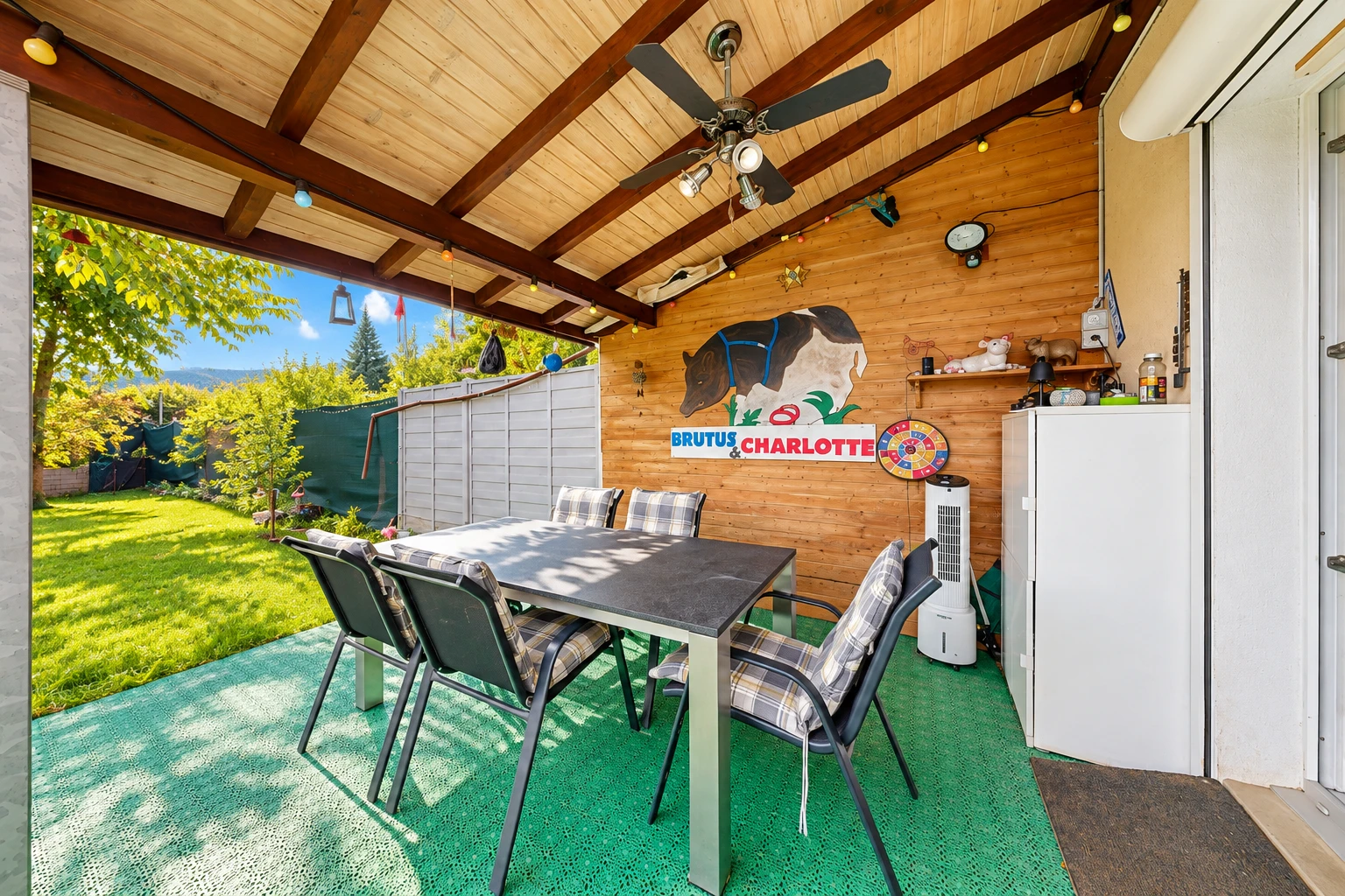 terrasse avec terrasse, ventilateur de plafond, coin repas extérieur, et pelouse