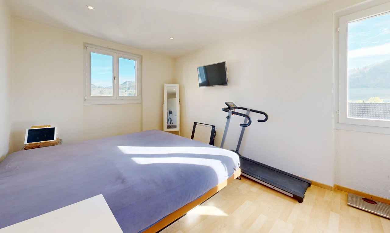 chambre avec cloison sèche, drywall, éclairage encastré, télévision, et sol en finition bois