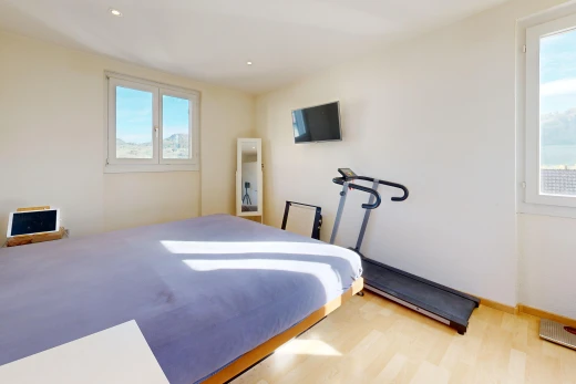 chambre avec cloison sèche, drywall, éclairage encastré, télévision, et sol en finition bois
