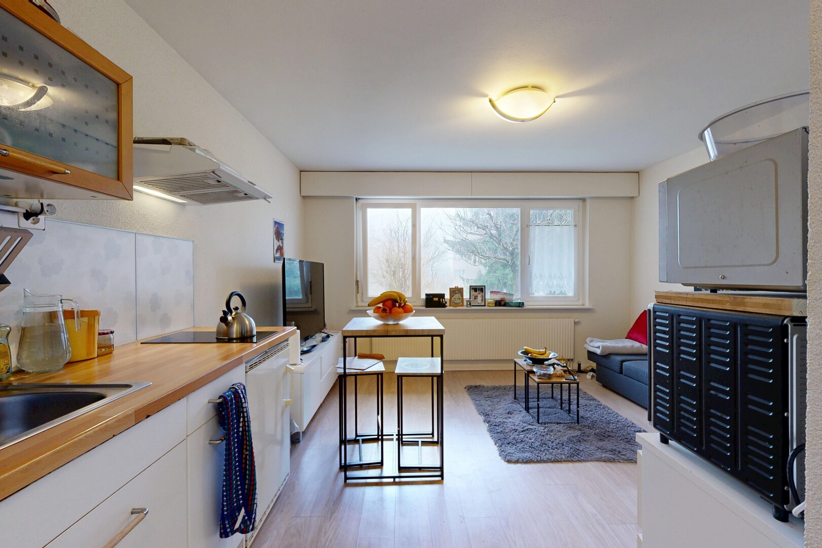 küche mit weiße schränke, dunstabzugshaube, arbeitsplatten, fernseher, und inside property
