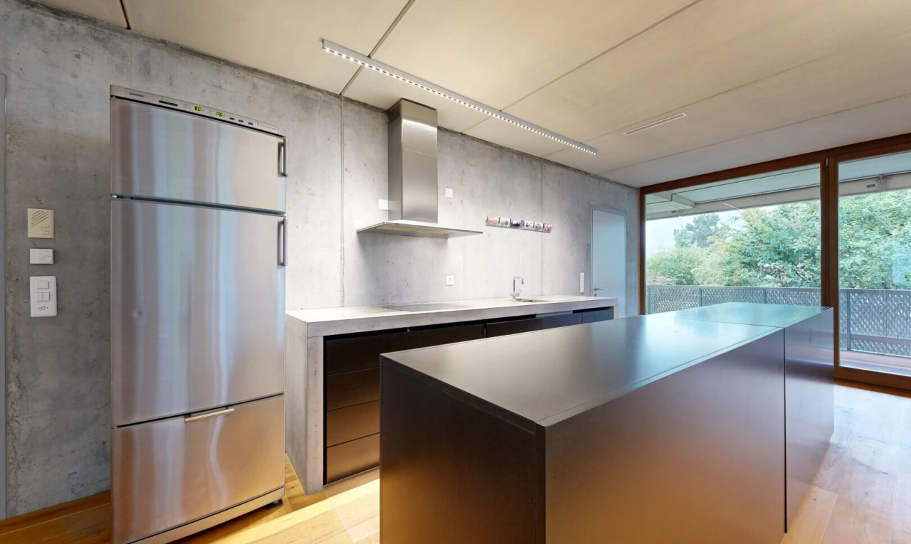 cuisine avec réfrigérateur, mur en béton, concrete wall, hotte, et light floor