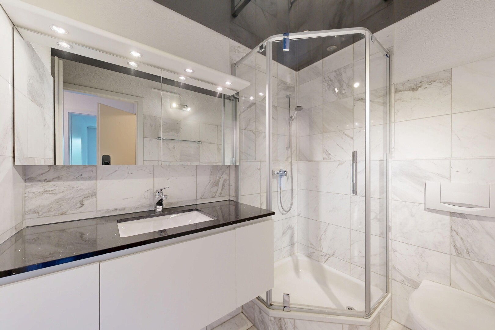 bathroom featuring vanity, a marble finish shower, and tile walls