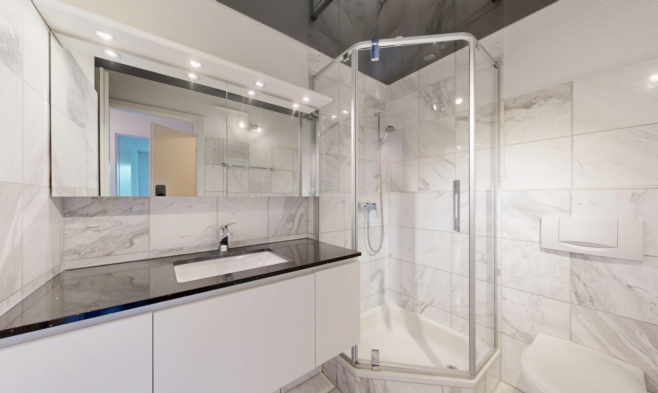 bathroom featuring vanity, a marble finish shower, and tile walls