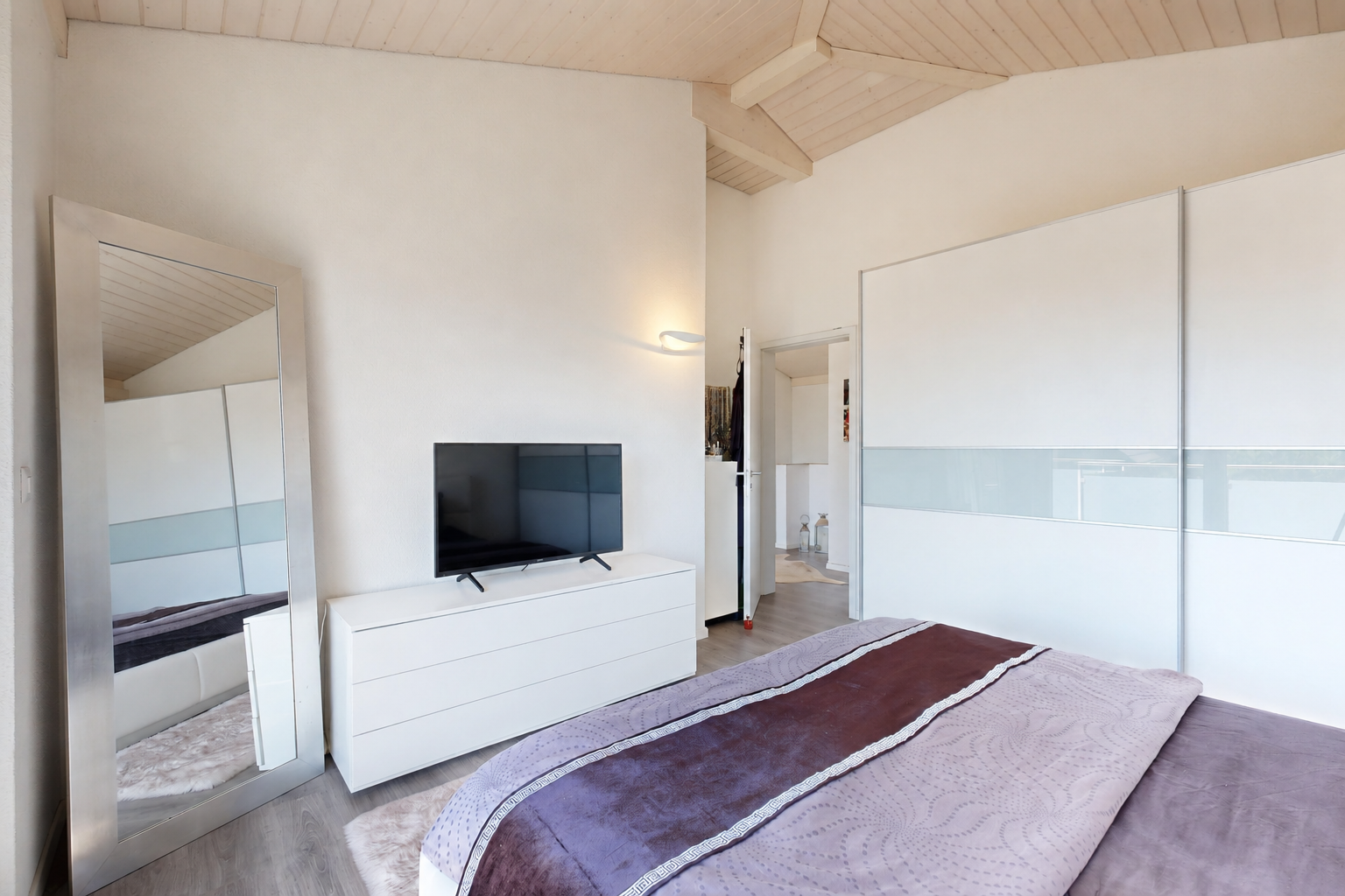 zimmer / schlafzimmer mit high end ceiling, balkendecke, beamed ceiling, fernseher, und dachschräge