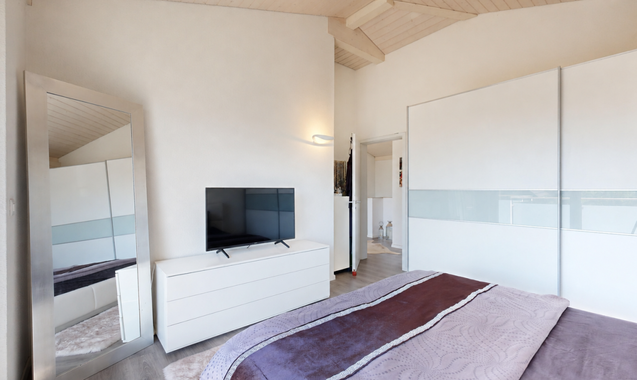 zimmer / schlafzimmer mit high end ceiling, balkendecke, beamed ceiling, fernseher, und dachschräge