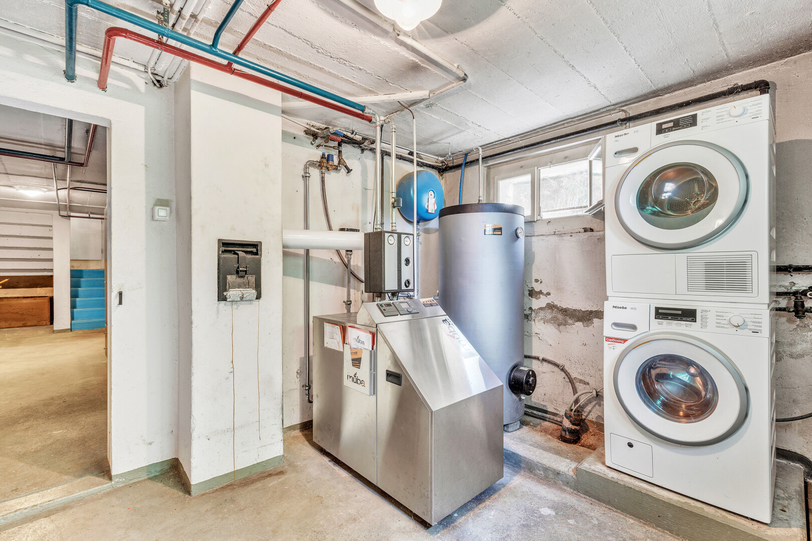 buanderie avec concrete floor, inside property, chauffe-eau, lave-linge et sèche-linge superposés, et sous-sol