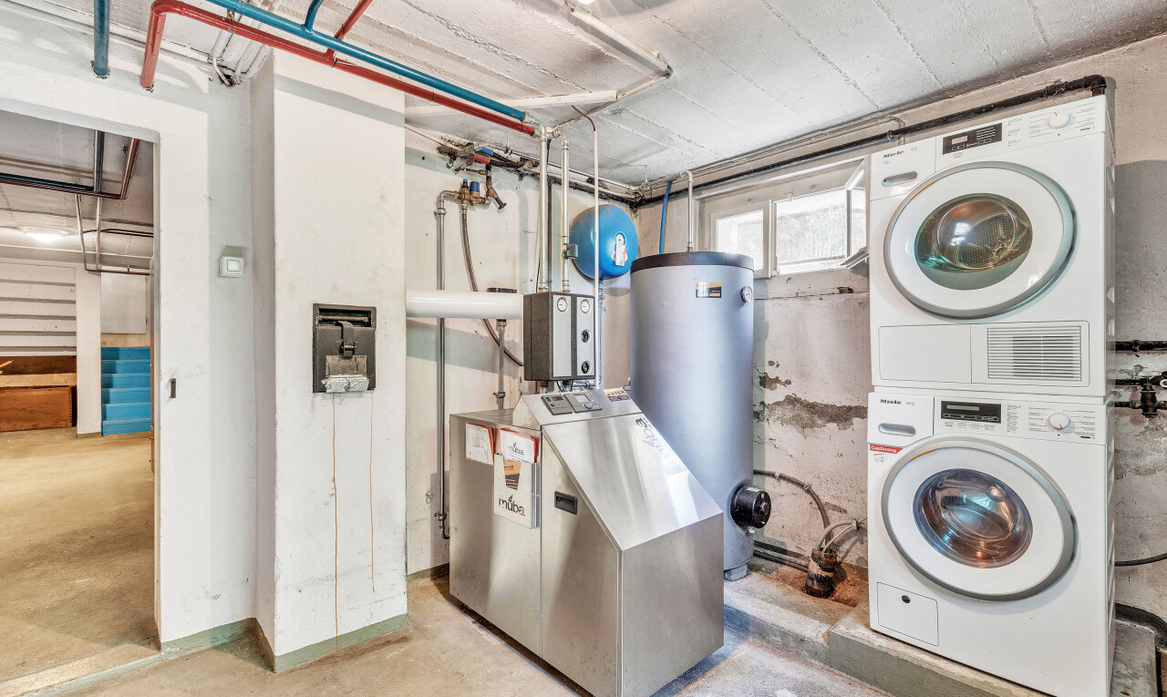 buanderie avec concrete floor, inside property, chauffe-eau, lave-linge et sèche-linge superposés, et sous-sol