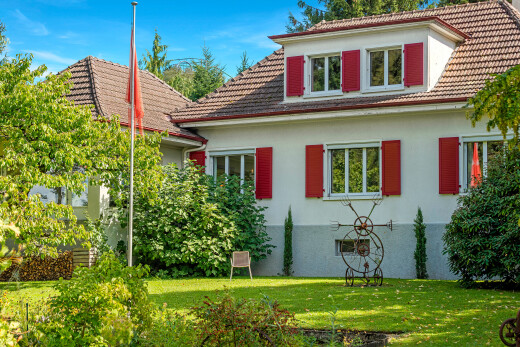 façade avec toit en tuiles, pelouse, bardage en stuc, property visible, et toit mansardé