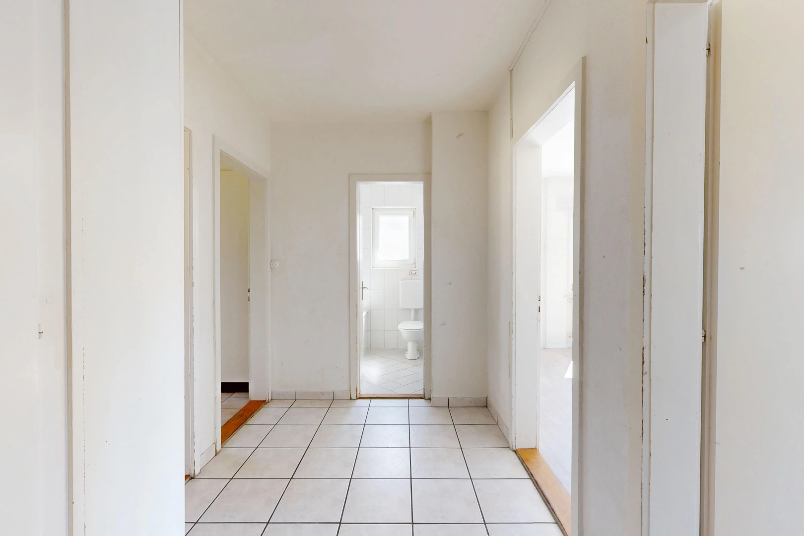 couloir avec light floor, tile floor, sol en carrelage, drywall, et cloison sèche