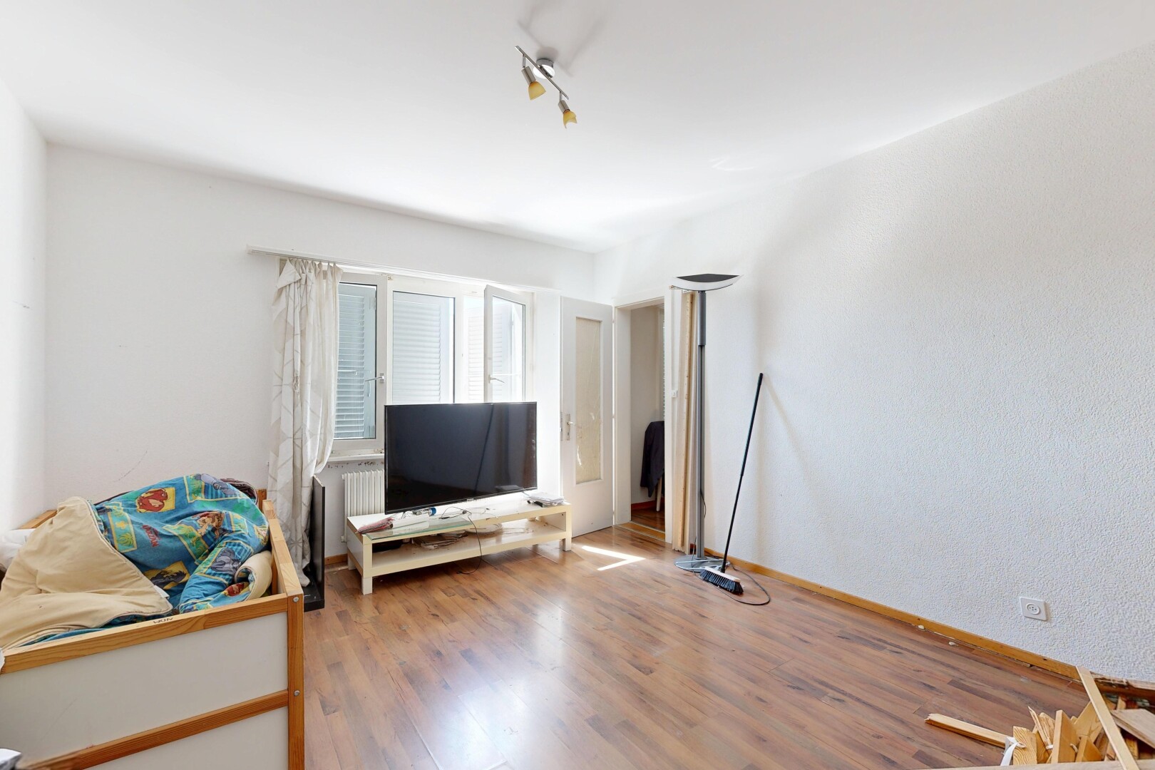 salon avec télévision, sol en finition bois, wood finish floor, éclairage sur rail, et track lighting