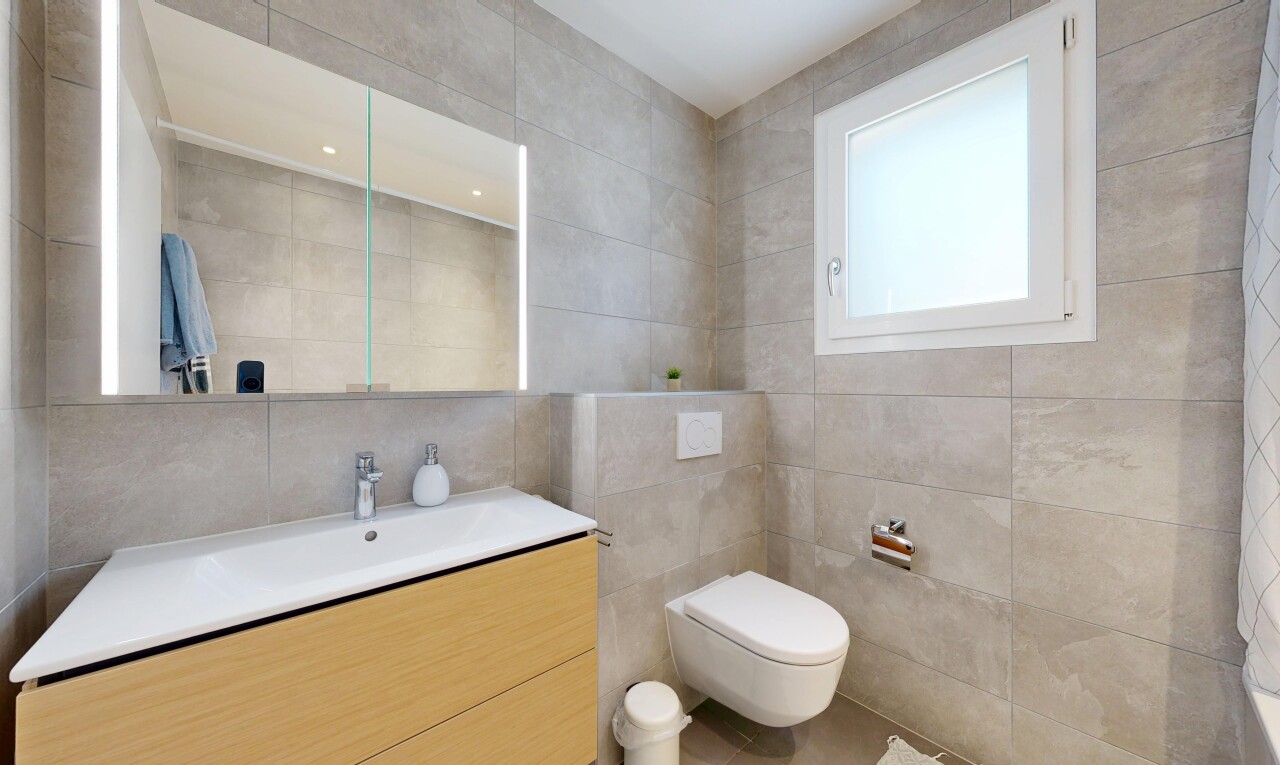 salle de bains avec mur en carrelage, tile wall, lavabo (ou coiffeuse selon le contexte), inside property, et lumière naturelle