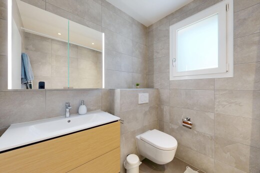 salle de bains avec mur en carrelage, tile wall, lavabo (ou coiffeuse selon le contexte), inside property, et lumière naturelle