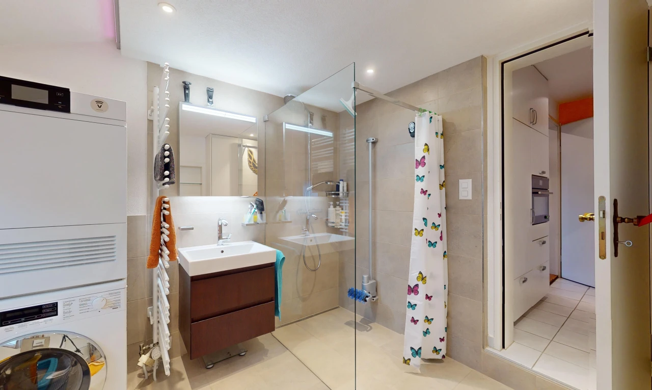 salle de bains avec carrelage, vasque, douche, meuble-lavabo, et machine à laver / sèche-linge superposés