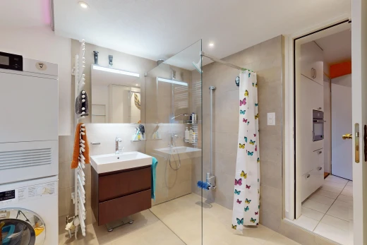 salle de bains avec carrelage, vasque, douche, meuble-lavabo, et machine à laver / sèche-linge superposés
