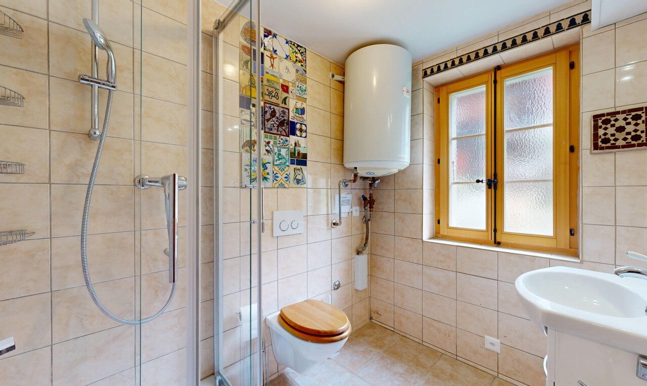 salle de bains avec douche, salle de bain complète, chauffe-eau, lavabo (ou coiffeuse selon le contexte), et mur en carrelage