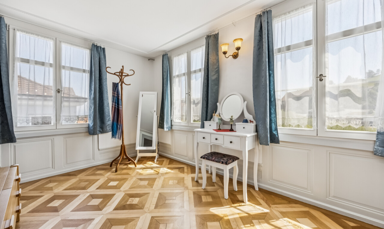 room with multiple windows, a decorative wall, and parquet floors