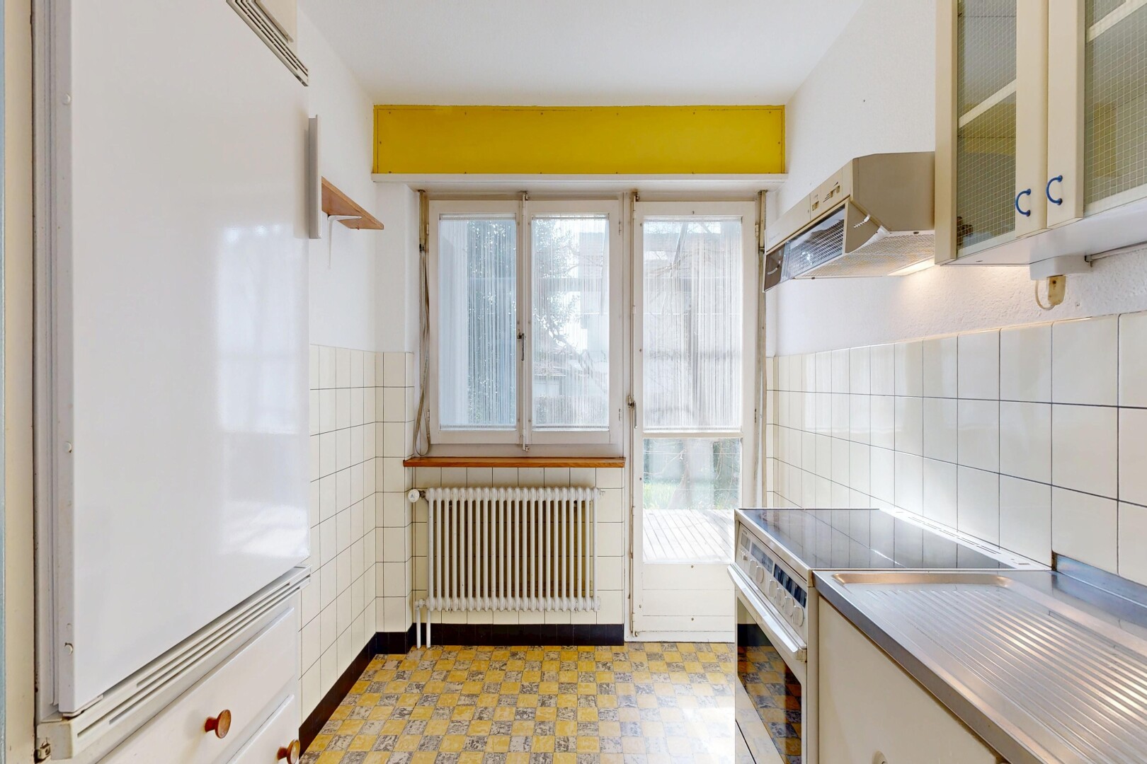 cuisine avec cuisinière, hotte, réfrigérateur, armoires avec insert en verre, et glass insert cabinets