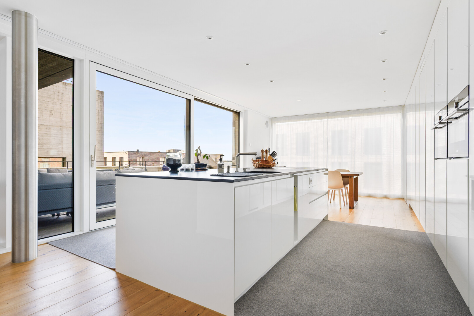 kitchen with floor to ceiling windows, light wood-style floors, white cabinetry, and an island with sink