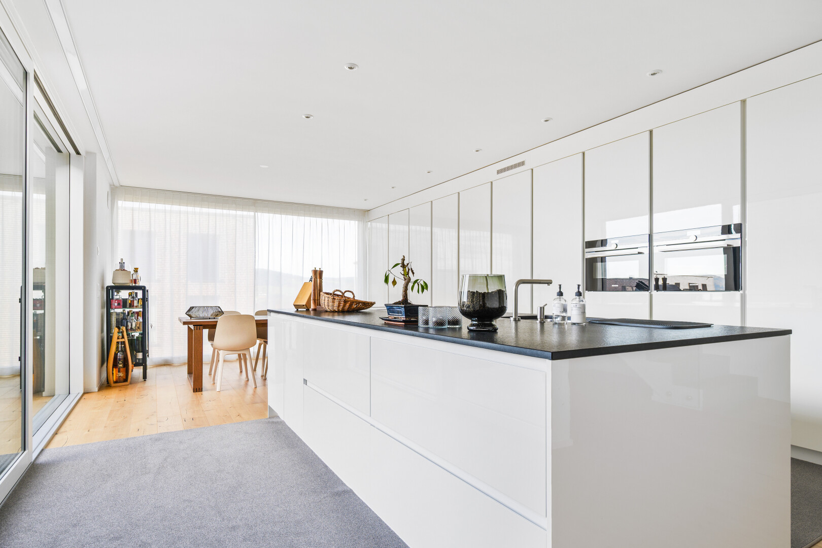 kitchen with modern cabinets, stainless steel double oven, white cabinets, a kitchen island, and dark countertops