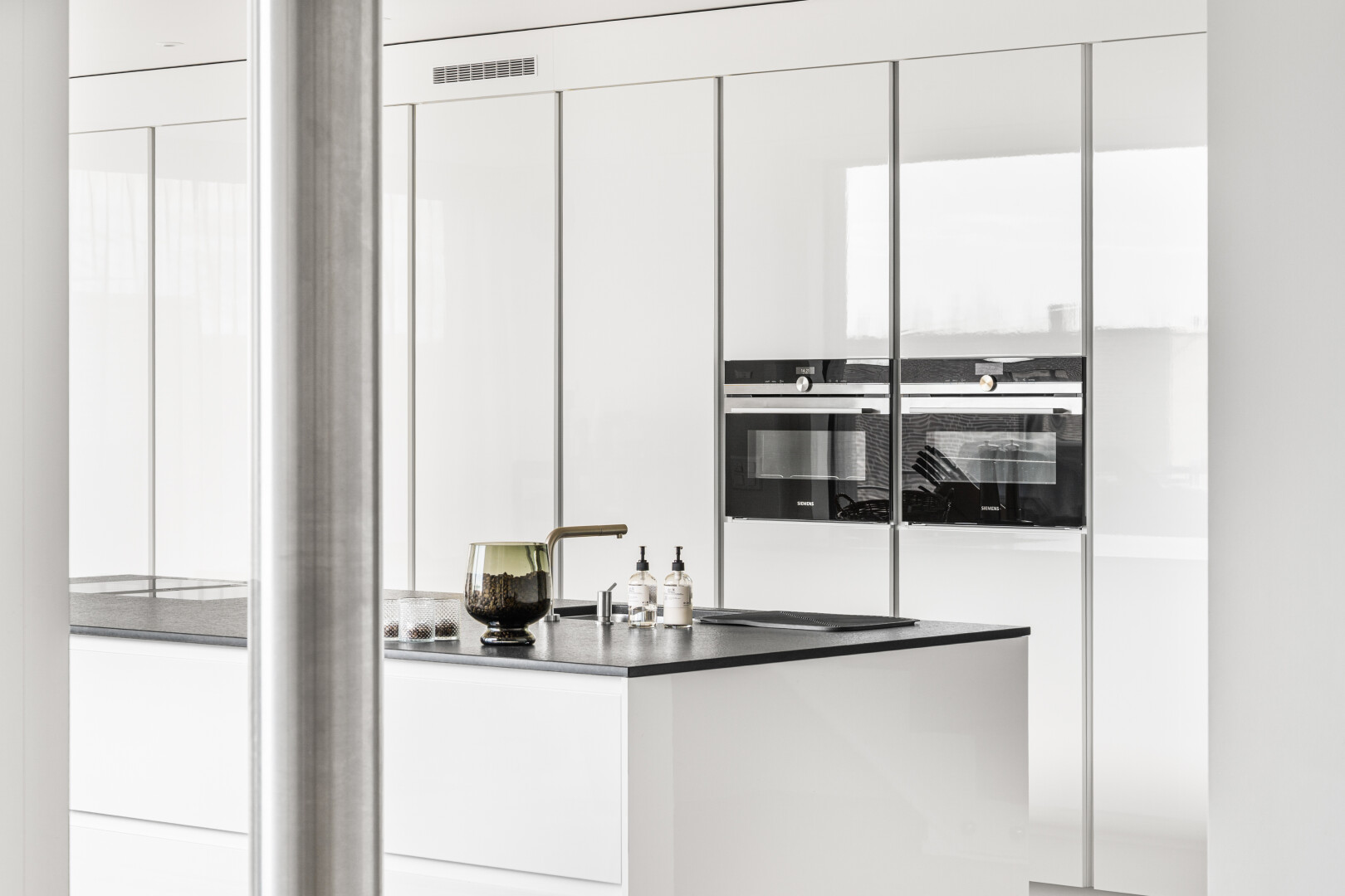 kitchen with white cabinets, stainless steel double oven, dark countertops, and modern cabinets