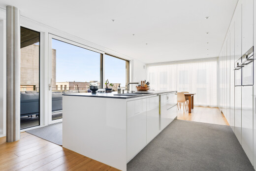 kitchen with floor to ceiling windows, light wood-style floors, white cabinetry, and an island with sink