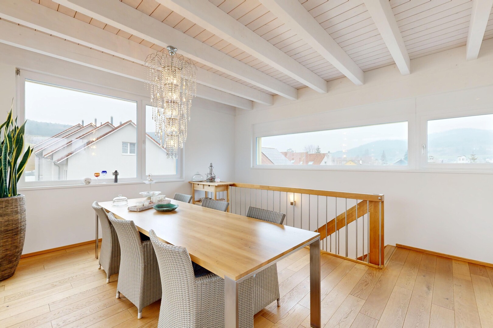 salle à manger avec sol en finition bois, lumière naturelle, lustre remarquable, et plafond à poutres