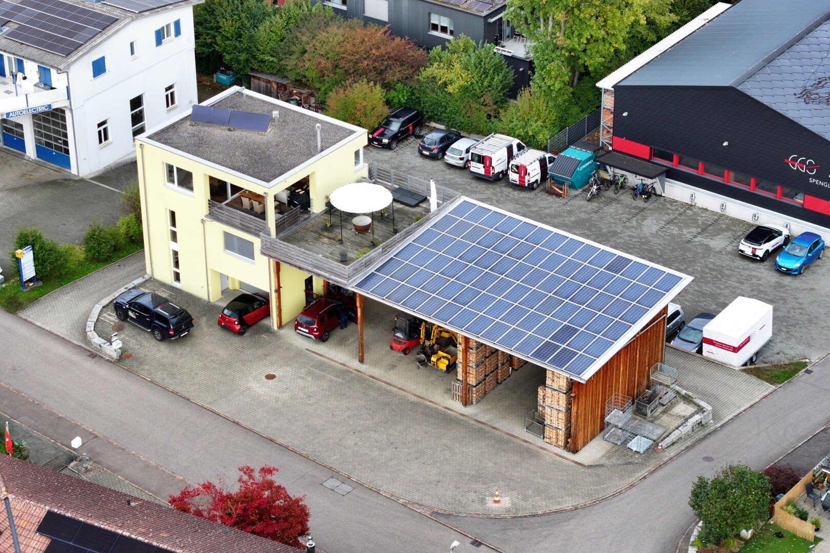 espace extérieur avec bardage en pierre, panneaux solaires, et parking