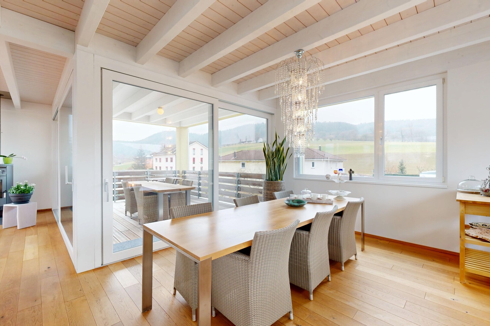 salle à manger avec sol en finition bois, lumière naturelle, et lustre remarquable