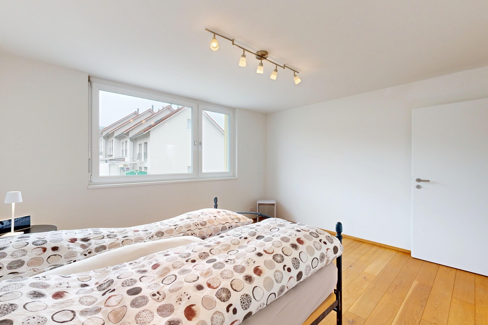 chambre avec sol en finition bois, lumière naturelle, éclairage sur rail, et cloison sèche