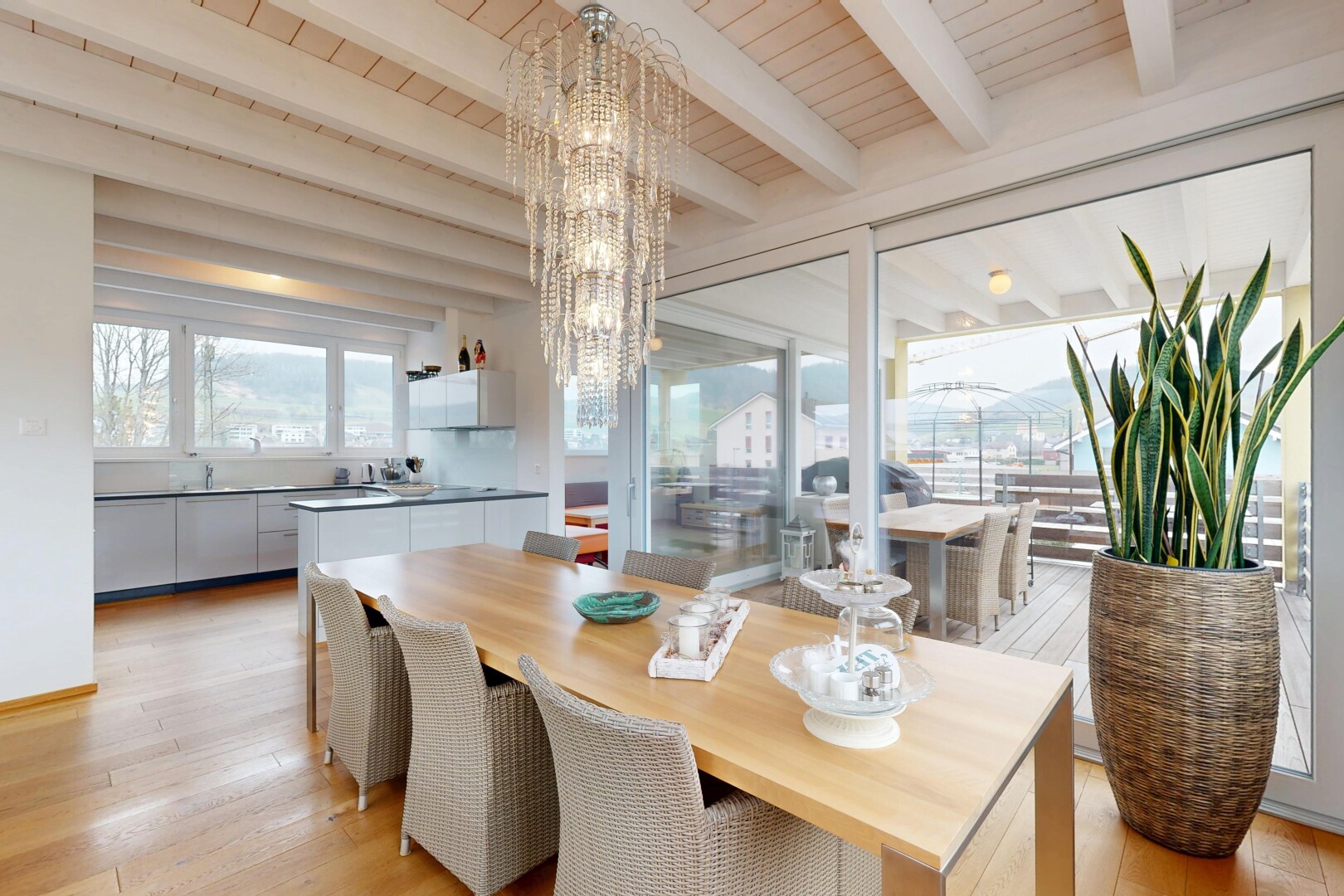 salle à manger avec plafond en bois, sol en finition bois, lumière naturelle, plafond à poutres, et lustre remarquable