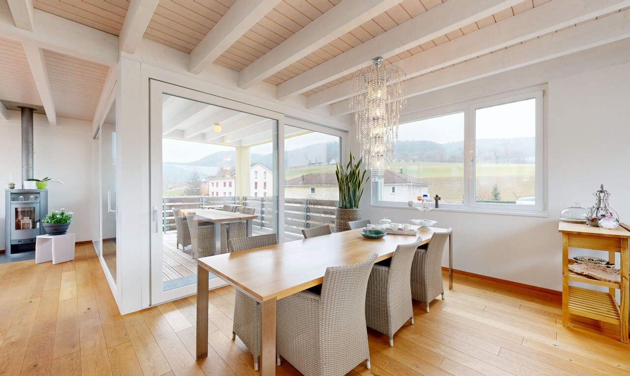 salle à manger avec sol en finition bois, lumière naturelle, et lustre remarquable