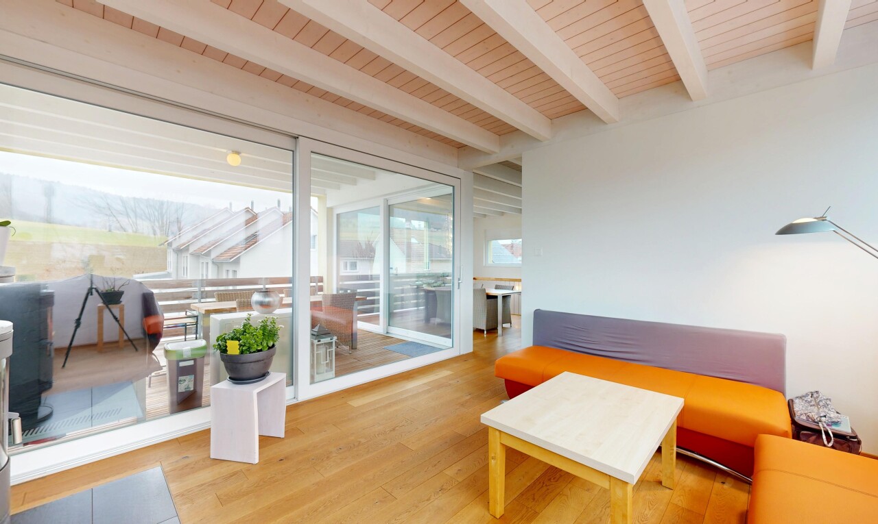 salon avec plafond en bois, sol en finition bois, plafond à poutres, lumière naturelle, et cloison sèche