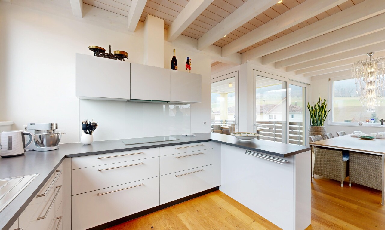 cuisine avec armoires blanches, plaque de cuisson, lumière naturelle, armoires à panneau plat, et plafond à poutres