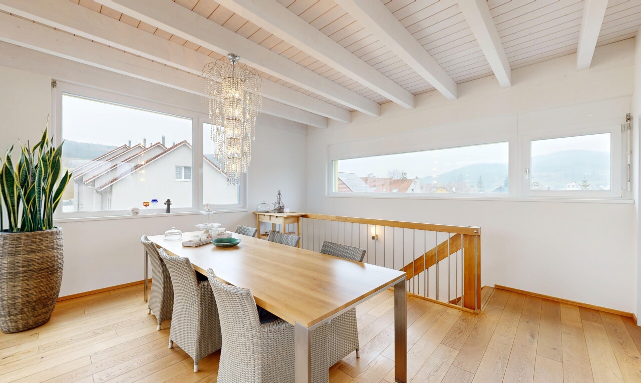 salle à manger avec sol en finition bois, lumière naturelle, lustre remarquable, et plafond à poutres