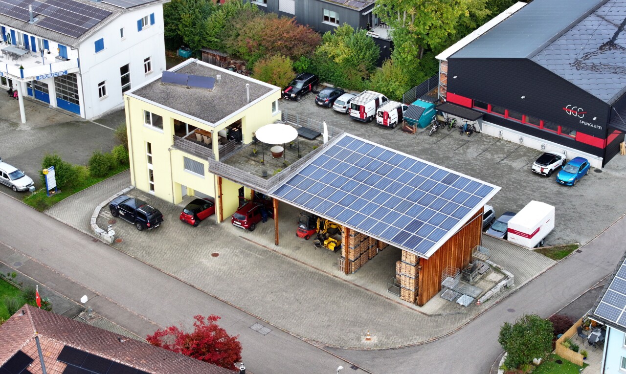 espace extérieur avec bardage en pierre, panneaux solaires, et parking