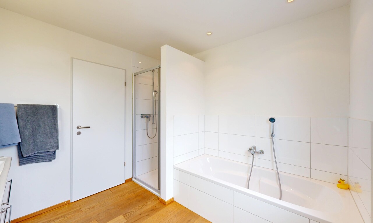 salle de bains avec cloison sèche, douche, sol en finition bois, salle de bain complète, et bain