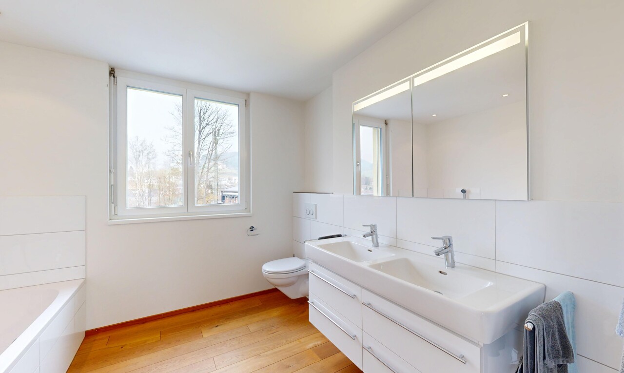 salle de bains avec toilette, sol en finition bois, évier, salle de bain complète, et lumière naturelle