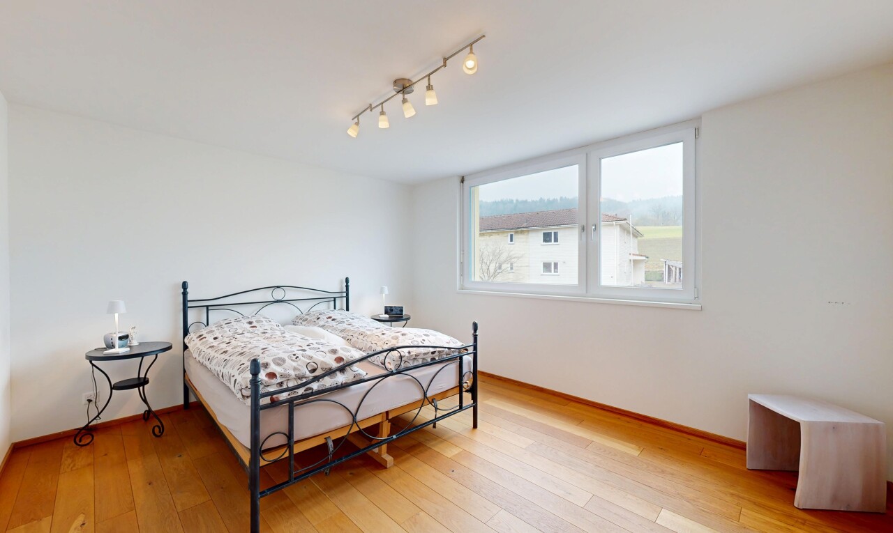 chambre avec cloison sèche, sol en finition bois, plinthes murales, lumière naturelle, et éclairage sur rail
