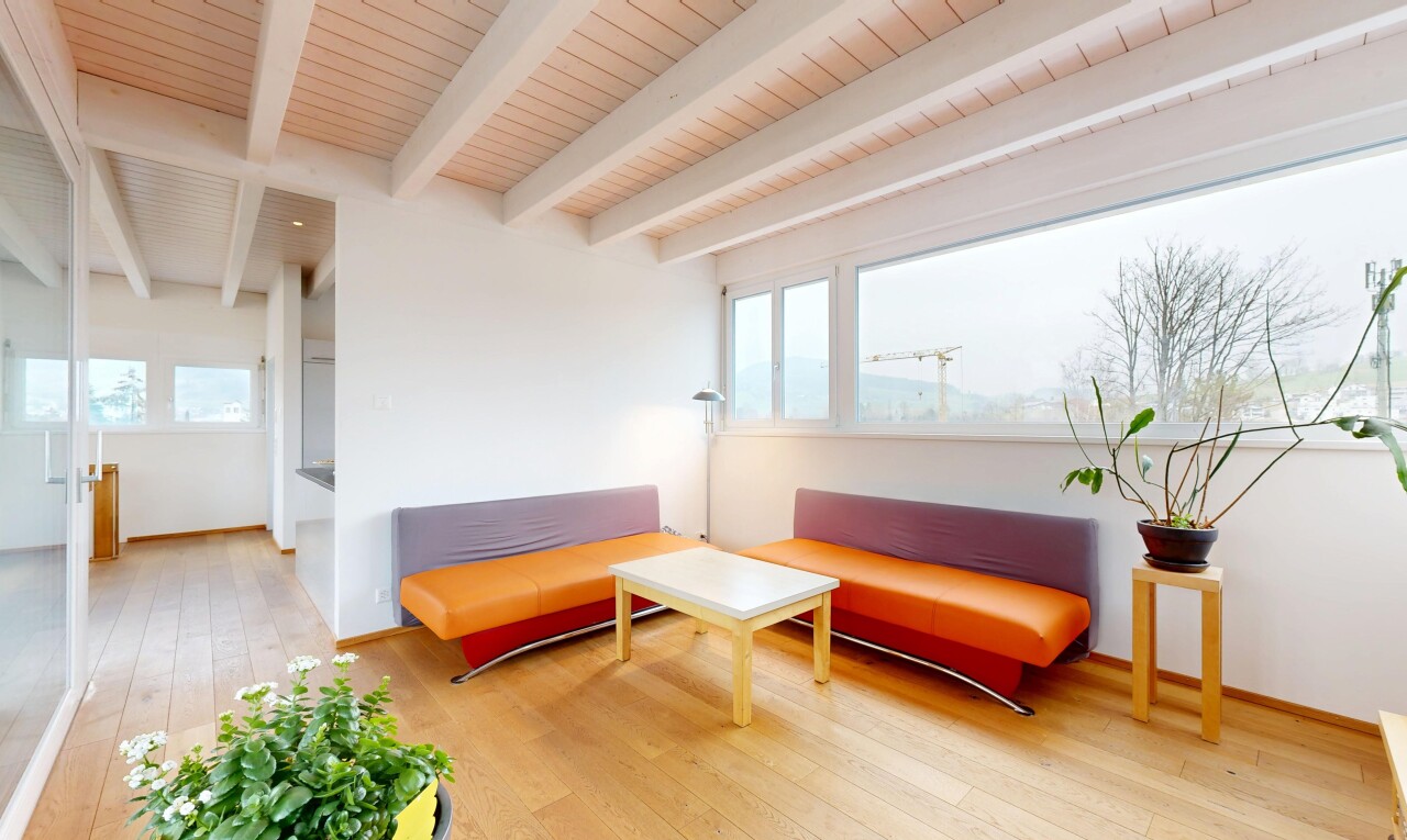 salon avec plafond à poutres, lumière naturelle, cloison sèche, sol en finition bois, et plinthes murales