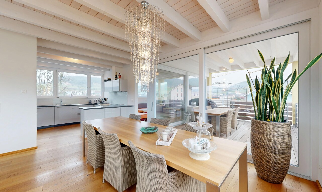 salle à manger avec plafond en bois, sol en finition bois, lumière naturelle, plafond à poutres, et lustre remarquable