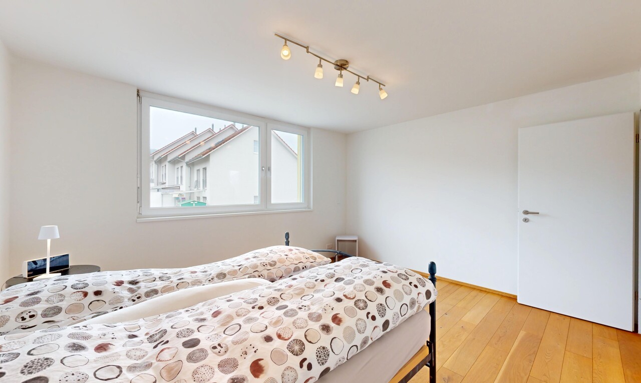 chambre avec sol en finition bois, lumière naturelle, éclairage sur rail, et cloison sèche