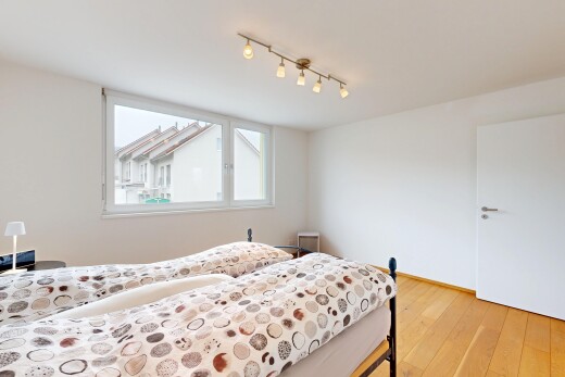 chambre avec sol en finition bois, lumière naturelle, éclairage sur rail, et cloison sèche
